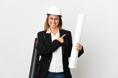 Miğferli orta yaşlı bir mimar kadın ve izole bir arka plan üzerinde planları var. Ürünü sunmak için yan tarafa bakıyor.