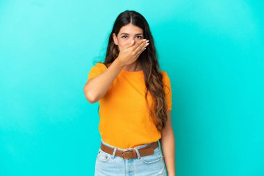 Mavi arka planda izole edilmiş, ağzı elle kaplanmış beyaz bir kadın.