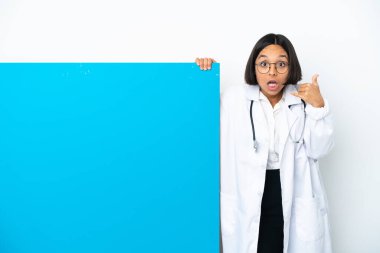 Beyaz arka planda izole edilmiş büyük bir afişi olan genç, melez bir doktor kadın telefon jesti yapıyor ve kuşkulanıyor.