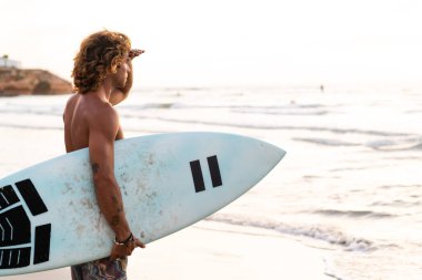 Kafkasyalı genç adam gün doğumunda sörf yapmak için erken kalkar.