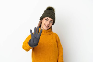 Kışlık şapkalı genç kız beyaz arka planda izole edilmiş mutlu ve parmakları olan dört kişi sayıyor.