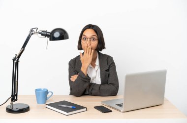 Ofiste çalışan, ağzı eliyle kapatan melez genç bir kadın.