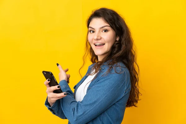 Έφηβη Ρωσίδα Απομονωμένη Κίτρινο Φόντο Χρησιμοποιώντας Κινητό Τηλέφωνο Και Δείχνοντας — Φωτογραφία Αρχείου