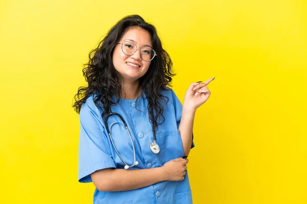 年轻的外科医生 亚洲女人 黄底孤立 手指指向侧边 — 图库照片