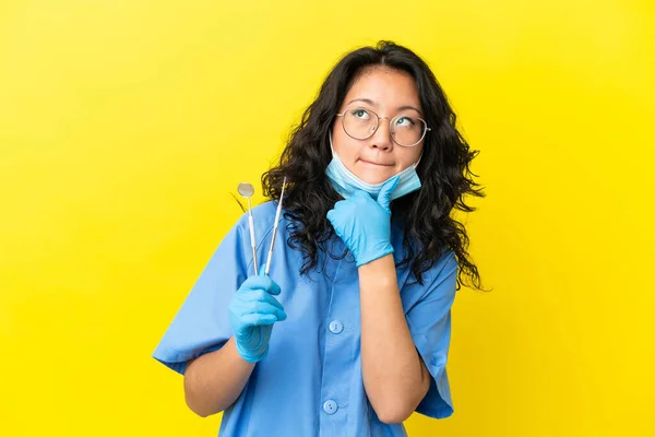 Junger Asiatischer Zahnarzt Mit Werkzeugen Über Isoliertem Hintergrund Mit Zweifeln — Stockfoto