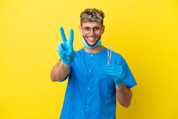Dentysta Biały Mężczyzna Trzyma Narzędzia Izolowane Żółtym Tle Uśmiechając Się — Zdjęcie stockowe