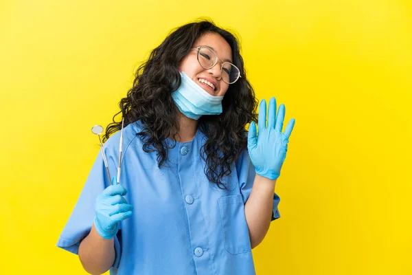 年轻的亚洲牙医拿着工具 带着愉快的表情举手表决孤立的背景 — 图库照片