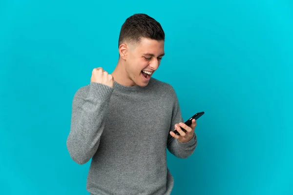 Joven Hombre Caucásico Aislado Sobre Fondo Azul Usando Teléfono Móvil —  Fotos de Stock