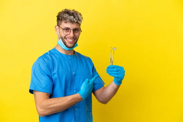 Dentysta Biały Mężczyzna Trzyma Narzędzia Izolowane Żółtym Tle Wskazując Tyłu — Zdjęcie stockowe
