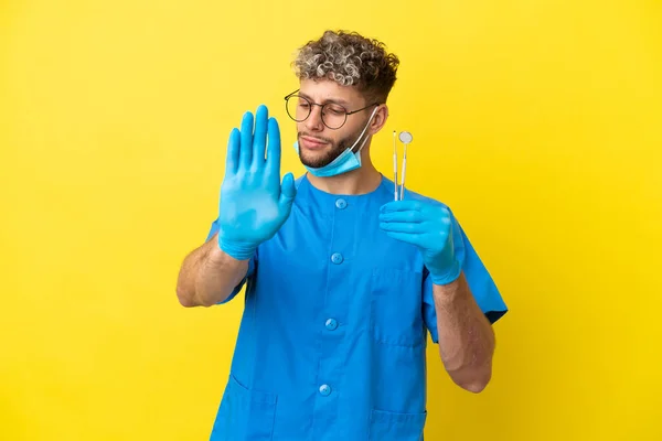 Dentysta Kaukaski Mężczyzna Trzyma Narzędzia Izolowane Żółtym Tle Stop Gest — Zdjęcie stockowe