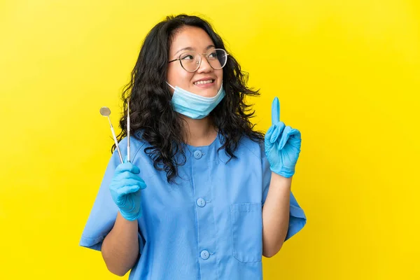 年轻的亚洲牙医在孤立的背景下拿着工具 提出了一个伟大的想法 — 图库照片