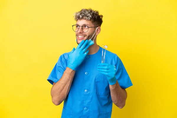 Dentista Caucasiano Homem Segurando Ferramentas Isoladas Fundo Amarelo Olhando Para — Fotografia de Stock