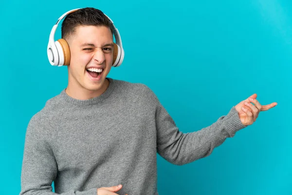 Jonge Blanke Man Geïsoleerd Blauwe Achtergrond Luisteren Muziek Doen Gitaar — Stockfoto