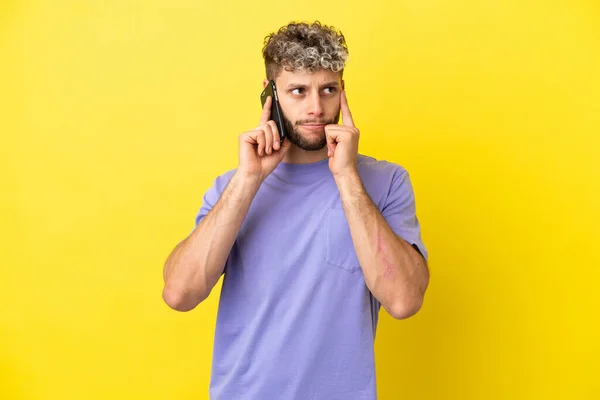 Jovem Caucasiano Usando Telefone Celular Isolado Fundo Amarelo Com Dúvidas — Fotografia de Stock