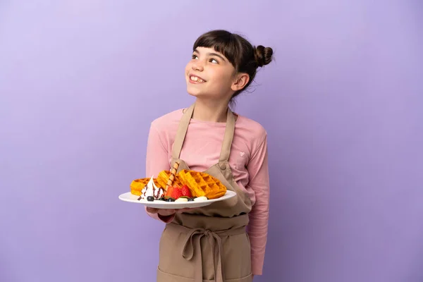 Menina Caucasiana Segurando Waffles Isolado Fundo Roxo Olhando Para Lado — Fotografia de Stock