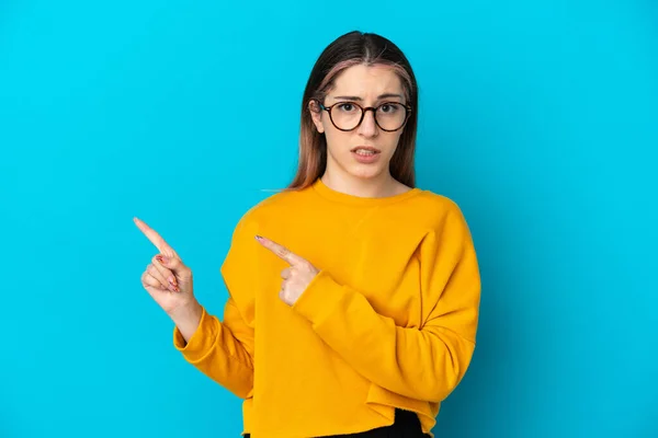 Jonge Blanke Vrouw Geïsoleerd Blauwe Achtergrond Bang Wijzend Naar Zijkant — Stockfoto