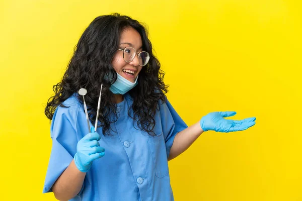 年轻的亚洲牙医把工具放在孤立的背景上 面带微笑地看着旁边 — 图库照片