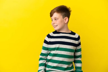 Sarı arka planda izole edilmiş küçük kızıl çocuk.