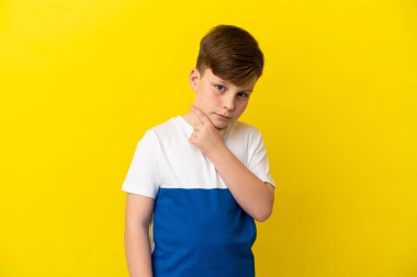 Küçük kızıl saçlı çocuk sarı arka planda izole edilmiş.