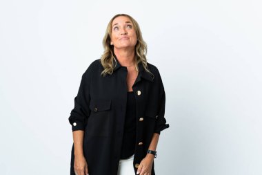 Orta yaşlı sarışın kadın, soyutlanmış beyaz arka planda, yukarı bakarken şüpheleri var.