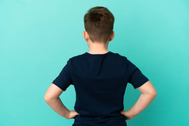 Küçük kızıl saçlı çocuk mavi arka planda izole edilmiş.