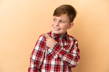 Bej arka planda izole edilmiş küçük kızıl saçlı çocuk.