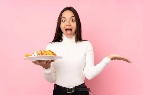 Young Brunette Woman Holding Waffles Isolated Pink Background Shocked Facial — Stock Photo, Image