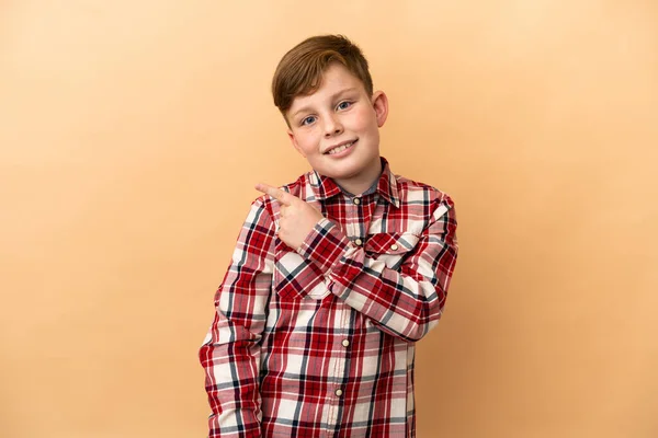 Pequeño Pelirrojo Aislado Sobre Fondo Beige Apuntando Hacia Lado Para —  Fotos de Stock