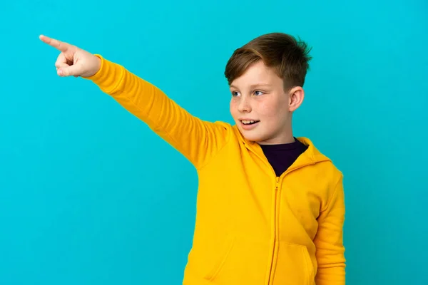 Little Redhead Boy Isolated Blue Background Pointing Away — Stock Photo, Image