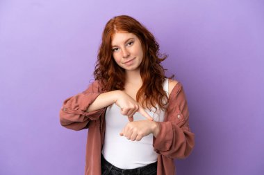 Mor arka planda genç bir kızıl kız geç kalma jesti yapıyor.