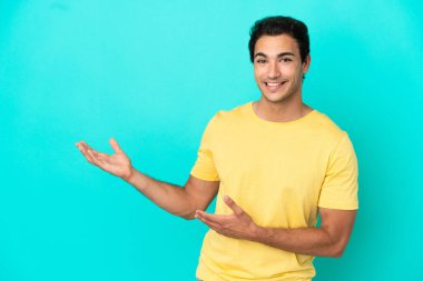 Izole mavi arka plan üzerinde Kafkas yakışıklı adam gelmeye davet için elleri yana uzatan