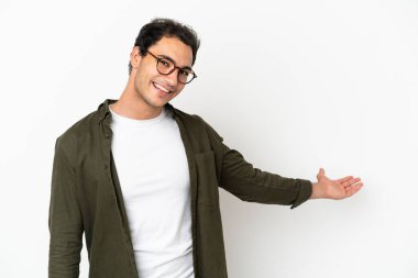 Beyaz tenli yakışıklı adam, soyutlanmış beyaz arka planda. Davet edilmek için ellerini yana uzatıyor.