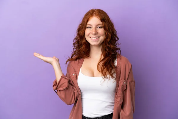 ティーンRedhead女の子上の隔離された紫色の背景を持っていますコピースペース想像上のザ手のひらに挿入する広告 — ストック写真