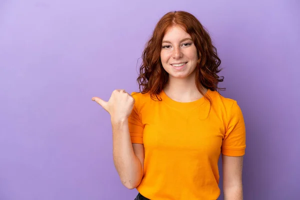 Adolescente Pelirroja Chica Sobre Aislado Púrpura Fondo Apuntando Lado Para — Foto de Stock