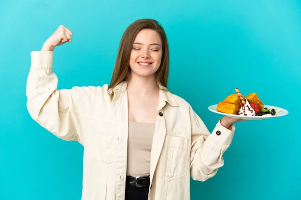 Adolescente Menina Segurando Waffles Sobre Fundo Azul Isolado Fazendo Gesto — Fotografia de Stock