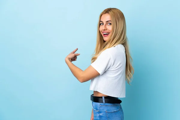 Ung Uruguayansk Blond Kvinna Över Isolerad Blå Bakgrund Pekar Tillbaka — Stockfoto