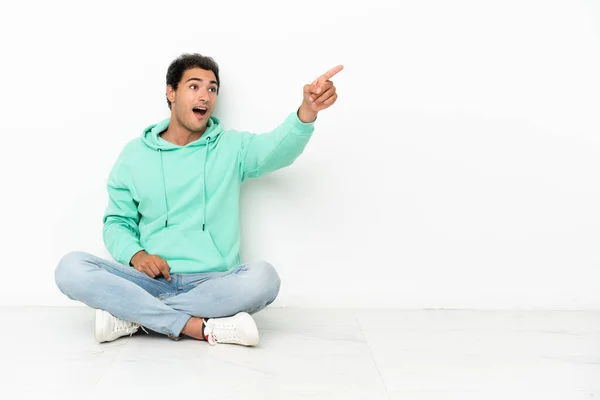 Caucasian Handsome Man Sitting Floor Pointing Away — Stock Photo, Image