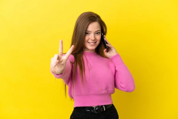 Adolescente Chica Usando Teléfono Móvil Sobre Aislado Amarillo Fondo Sonriendo —  Fotos de Stock