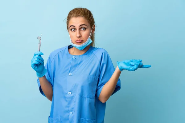 Mladá Žena Zubař Drží Nástroje Přes Izolované Modré Pozadí Ukazuje — Stock fotografie