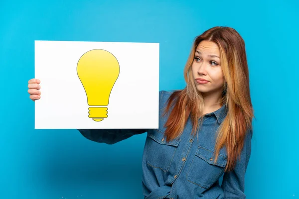 Teenager Girl Isolated Blue Background Holding Placard Bulb Icon — Stock Photo, Image