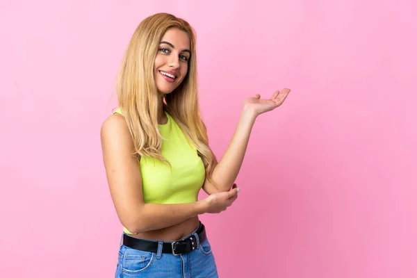 Jovem Mulher Loira Uruguaia Sobre Fundo Rosa Isolado Estendendo Mãos — Fotografia de Stock