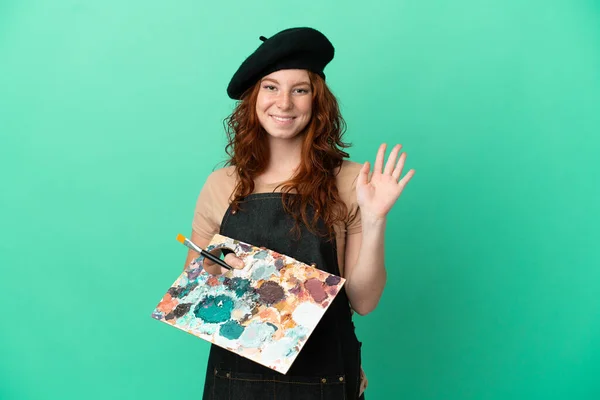 Nastoletni Rudowłosy Artysta Trzymając Paletę Odizolowanych Zielonym Tle Salutując Ręki — Zdjęcie stockowe