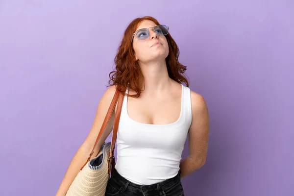ティーネージャーRedhead女の子保持Aビーチバッグ孤立した上に紫の背景と検索アップ — ストック写真
