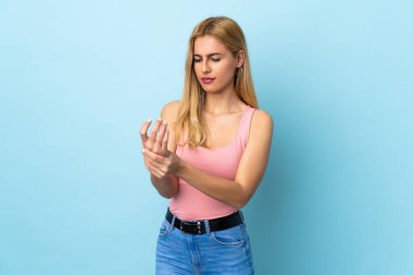 Genç Uruguaylı sarışın kadın izole edilmiş mavi arka planda acı çekiyor.