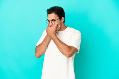 Kafkasyalı yakışıklı bir adam, izole edilmiş mavi arka planda, ağzı kapalı ve yana bakıyor.