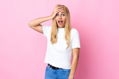 Genç Uruguaylı sarışın kadın pembe arka planda. Yan tarafa bakarken sürpriz jest yapıyor.