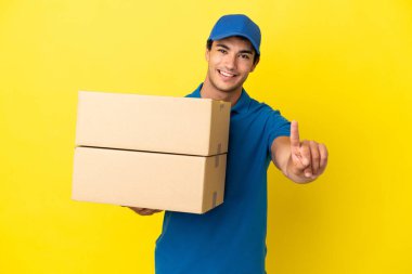 Teslimatçı, izole edilmiş sarı duvarın üzerinde parmağını kaldırıyor.