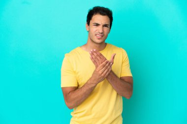 Caucasian handsome man over isolated blue background suffering from pain in hands