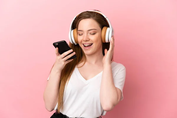 분홍색 배경을 소녀가 핸드폰으로 음악을 노래를 부른다 — 스톡 사진
