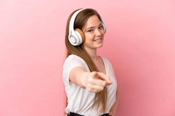 Teenager Girl Isolated Pink Background Listening Music Pointing Front — 스톡 사진